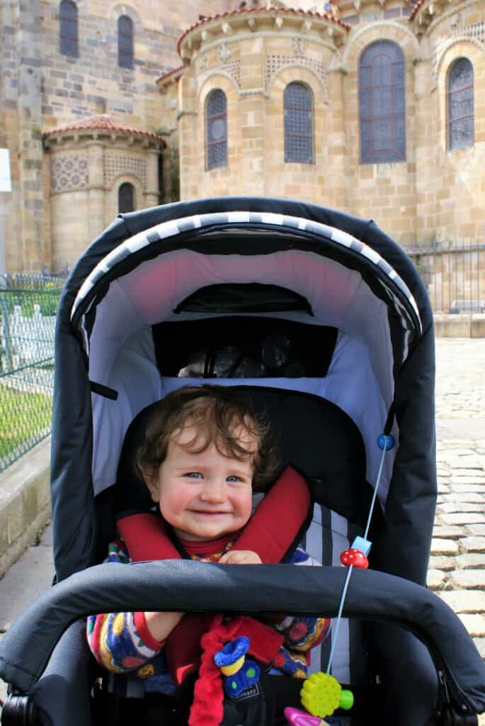 Baby in Kinderwagen vor Kirche