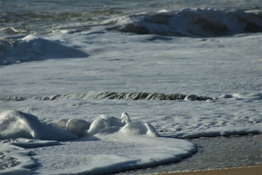 Wellen kommen mit viel Gischt am Strand an