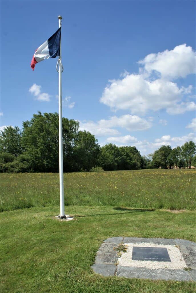 Gedenkplatte Bouvron auf Wiese mit Fahnenmast und französischer Flagge