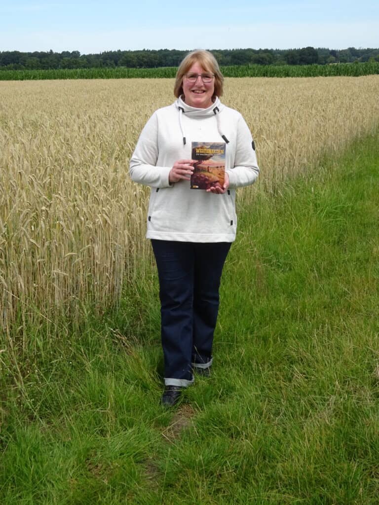 Birgit Susemihl vor einem Feld mit ihrem Buch