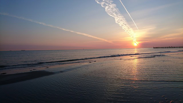 Sonnenaufgang am Meer mit Kondensstreifen