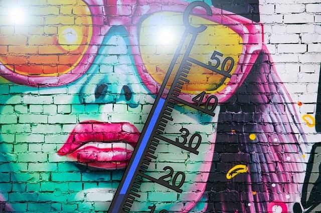 Graffiti mit grünem Gesicht einer Person mit pinkfarbener Sonnenbrille, davor ein Thermometer