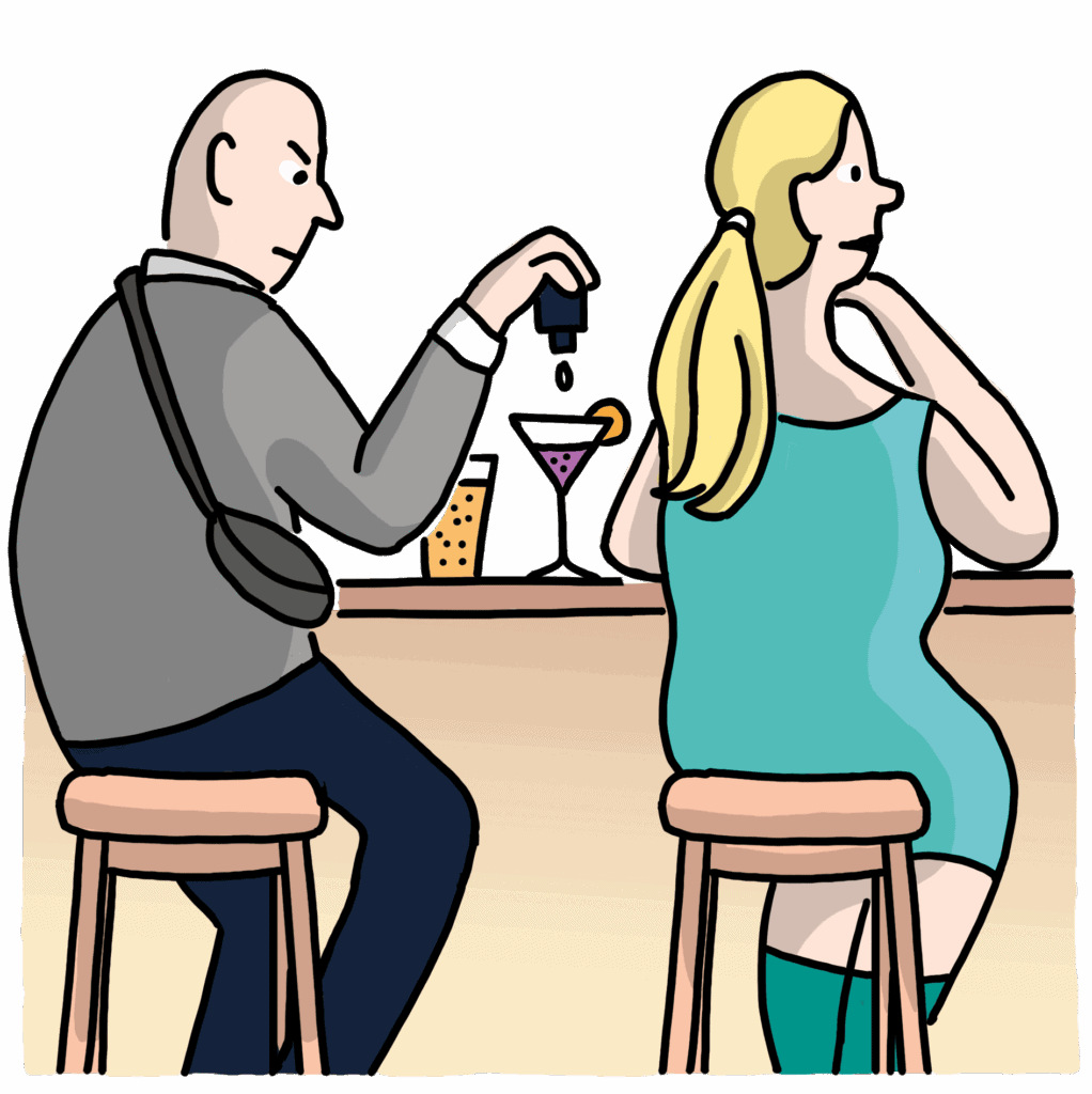 Ein Mann und eine Frau sitzen auf Barhockern an einer Bar. Während die Frau wegsieht, gibt der Mann Tropfen in ihr Cocktailglas.